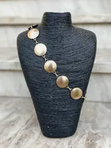 Cinto dorado de metal con eslabones y monedas circulares texturizadas.