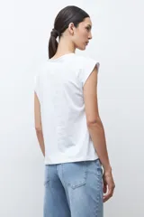Remera de manga corta color verde petróleo, con cuello redondo y detalle de abertura tipo gota en el frente. Presenta un diseño con bordados geométricos tono sobre tono en la parte frontal.