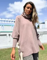 Polerón de cuello alto y corte oversize, color rosado, con mangas largas de puño acanalado y detalle de ojalillos metálicos con tiras en los laterales.