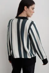 Buzo tipo polo de punto de algodón con diseño de rayas verticales en color blanco y verde oscuro. Presenta cuello y puños en color negro, cierre frontal con botones y corte recto.