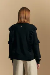 Sweater negro de manga larga, tejido suave y caída liviana, con volados en el delantero y mangas. Silueta recta.