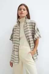 Capa acampanada con manga corta, cierre metálico a la vista, cuello recto y bolsillos con tapa. Terminaciones envivadas. Prenda informal, de uso diario. Se puede usar todo el año. Tela 100% lana fina sin teñir, diseñada exclusivamente por Don Baez. Hecha 100% en Uruguay.