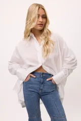 Camisa blanca oversize de algodón con cuello clásico, mangas largas y puños abotonados con detalle de tablas.