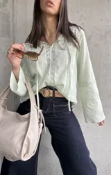 Blusa verde agua con detalles de encaje, mangas largas acampanadas y lazos en el escote.