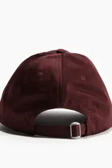 Gorra color borgoña de sarga de algodón con ojales bordados y correa ajustable con hebilla metálica en la parte trasera.