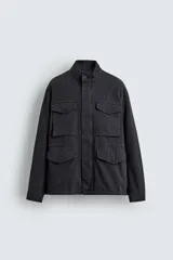 Cazadora regular fit de algodón color gris oscuro con efecto lavado, cuello subido, manga larga y cierre frontal con cremallera oculta por solapa con botones a presión. Cuenta con cuatro bolsillos frontales de plastrón con solapa y cintura ajustable con cordón interior.