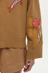 Cardigan tejido de algodón color camel con cuello en V, cierre frontal de botones y bordados coloridos con motivos variados.