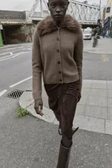 Chaqueta de punto color marrón con cuello de solapa desmontable en pelo sintético. Presenta cierre frontal con botones, manga larga y terminaciones en rib.