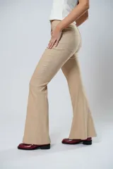 Pantalón de tiro alto color beige, con cierre frontal con cremallera y botón, bolsillos delanteros y traseros, y corte evasé en el bajo.