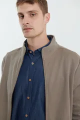 Cardigan de tejido de punto color verde militar, con cierre frontal de metal y cuello redondo. Presenta detalle de tejido plano en la cartera del cierre y en los bolsillos laterales.