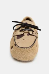 Mocasín de piel con pelo y estampado animal, con detalle de cordones en el empeine y pespuntes decorativos.