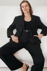 Blazer negro de corte recto, con cuello de solapa con muesca, manga larga con hombreras y cierre frontal con dos botones.