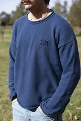 Sweater de lana azul marino, de corte holgado, con cuello redondo y mangas largas. Cuenta con las iniciales 'SM' bordadas en el pecho en hilo negro.