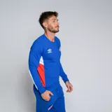 Buzo deportivo de manga larga, color azul, con cuello redondo y detalles en rojo y blanco en los laterales. Presenta el logo de Umbro y el escudo del Club Nacional de Football en el pecho.