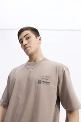 Remera de manga corta color topo, con escote redondo y fit regular. Presenta un pequeño estampado en el pecho con texto manuscrito y un código QR.