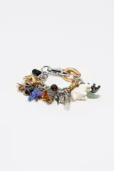 Pulsera de cadena metálica con múltiples dijes colgantes de diversos materiales, incluyendo figuras de animales, piedras naturales, elementos de resina y piezas metálicas en tonos dorados y plateados. Cuenta con cierre de mosquetón.