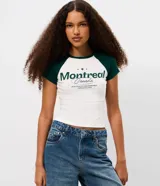 Remera de algodón con diseño tipo ringer, de corte ajustado y mangas cortas con sisa raglán en color verde oscuro. Presenta estampa frontal con lettering Montreal y detalles en color blanco.
