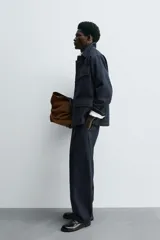 Pantalón de corte barrel fit confeccionado en denim de algodón rígido color azul oscuro. Presenta cintura con pliegues frontales, bolsillos laterales y bolsillos traseros de vivo. Cierre frontal con cremallera y gancho metálico oculto.