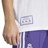 Camiseta de fútbol Adidas del Real Madrid, inspirada en los modelos de los años 80. Diseño blanco con detalles en violeta, logo de Adidas y escudo del club bordados. Corte holgado.