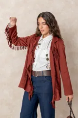 Chaqueta de gamuza color terracota con diseño de flecos en el frente y las mangas. Presenta cuello solapa, cierre frontal y bolsillos delanteros.