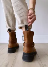 Bota de cuero color marrón con suela de goma negra, cierre lateral y pulsera desmontable con hebilla.