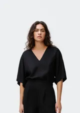 Blusa negra de manga corta, con escote pronunciado en V y corte holgado.