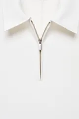 Vestido midi de tejido fluido y diseño entallado, con cuello de solapa y cierre frontal de cremallera. Presenta un corte sin mangas y un estilo minimalista.