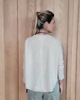 Sweater de punto color beige, con cuello en V, manga larga con puños acanalados y diseño holgado.