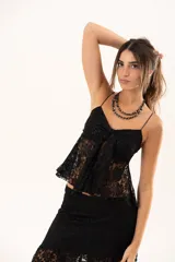 Top de encaje negro con breteles finos, escote con detalle de nudo frontal y diseño con apertura central.