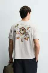 Camiseta de corte relajado, color gris jaspeado, con cuello redondo y manga corta. Presenta un parche rectangular azul marino en el centro del pecho con texto estampado en blanco y una frase adicional debajo.