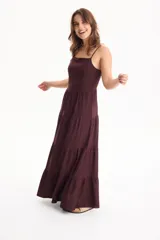 Vestido largo color blanco, confeccionado en lino, con tiras finas regulables, escote recto y falda amplia de corte acampanado con volados escalonados.
