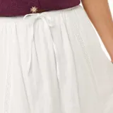 Falda larga acampanada color blanco, con detalles de inserciones de encaje de macramé y diseño escalonado.