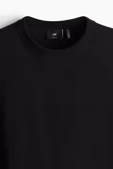 Remera negra de punto pesado con cuello redondo ribeteado, hombros caídos y bajo recto. Corte holgado confeccionada con tejido funcional COOLMAX®, una fibra de poliéster de secado rápido que elimina la humedad y regula la temperatura corporal.