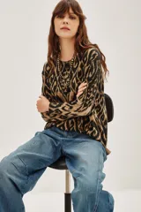 Sweater de punto con cuello redondo y manga larga, presentando un estampado tipo ikat o animal print abstracto en tonos marrón claro y negro/gris oscuro.