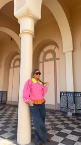 Camisa de manga larga en color rosa, con cuello Peter Pan en color amarillo y detalle de volados en los bordes. Presenta cierre frontal con botones y puños elásticos con detalle de volados.