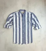 Camisa de algodón con rayas verticales anchas en azul y blanco, cuello mao, manga larga con puños abotonados y logo bordado en el pecho.