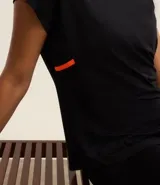 Remera deportiva negra de microfibra de poliamida, con cuello redondo, mangas cortas y franja lateral contrastante color naranja.