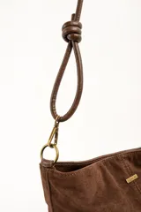 Cartera tipo bandolera de gamuza sintética color marrón, con asa larga decorada con nudos y detalles de herrajes metálicos dorados.