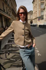 Chaqueta color tostado con efecto ante, cuello redondo y manga larga. Presenta detalles de acabados trenzados en el cuello, el cierre frontal, los puños y el bajo. Cuenta con cierre frontal de botones y bolsillos delanteros de vivo.