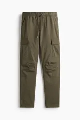 Pantalón cargo de corte ajustado en tejido de algodón, con cintura elástica y cordón de ajuste. Presenta bolsillos laterales tipo cargo con solapa, bolsillos al bies y bolsillos traseros. Incluye costuras reforzadas y pinzas en las rodillas para mayor movilidad.