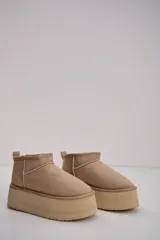 Bota corta tipo botineta en color beige, con diseño de caña baja y plataforma gruesa de goma al tono. Presenta costuras reforzadas y tirador en la parte posterior.