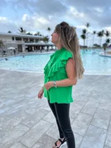 Camisa verde brillante de muselina con volados en el frente y tachas plateadas.