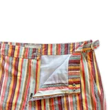 Short de baño con estampado geométrico en tonos tierra, naranja y violeta. Cuenta con pretina fija, hebillas metálicas laterales para ajuste, cierre frontal con botón a presión y tres bolsillos. Incluye interior con mesh hipoalergénico.