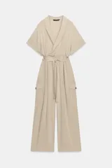 Mono largo de cuello solapa y escote en pico cruzado, con mangas cortas. Presenta bolsillos laterales de plastrón con solapa y botones, y un cinturón del mismo tejido para ajustar en la cintura. Cierre frontal con cremallera y botón interior.