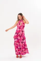 Vestido largo fucsia con estampado abstracto, cuello halter con abertura en forma de lágrima y volados en la falda.