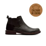 Bota casual tipo Chelsea de cuero negro, con panel elástico lateral, detalle de tira con remache metálico y refuerzo de gamuza en el talón. Presenta una suela de madera con base de goma.
