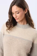 Buzo tejido de punto con diseño de bloques de color en tonos rosa, beige y gris. Presenta cuello redondo, mangas largas y corte holgado.