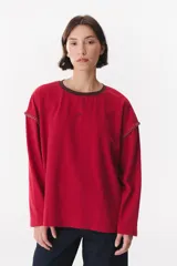 Remera de manga larga con corte oversized, color azul marino con cuello redondo en contraste color marrón. Presenta costuras decorativas a contratono hechas a mano en la zona de los hombros y logo bordado en el centro del pecho.