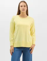 Buzo de tejido fino color amarillo, con cuello redondo, manga larga con puños acanalados y pespunte central vertical en el frente y la espalda. Presenta un ruedo ancho acanalado con tajos laterales.