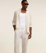 Pantalón de lino blanco de corte recto, con trabillas en la cintura, cierre tradicional y bolsillos laterales.